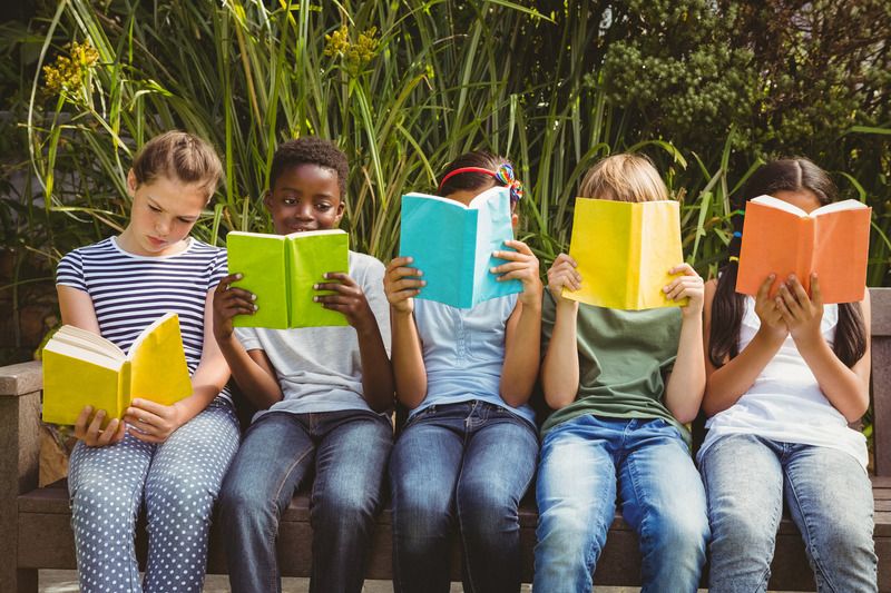 Five children sitting on a bench, each reading a brightly colored book.